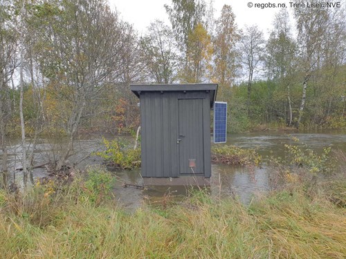 Bilde av instrumenthytte for vannføring som er omringet av flomvann.