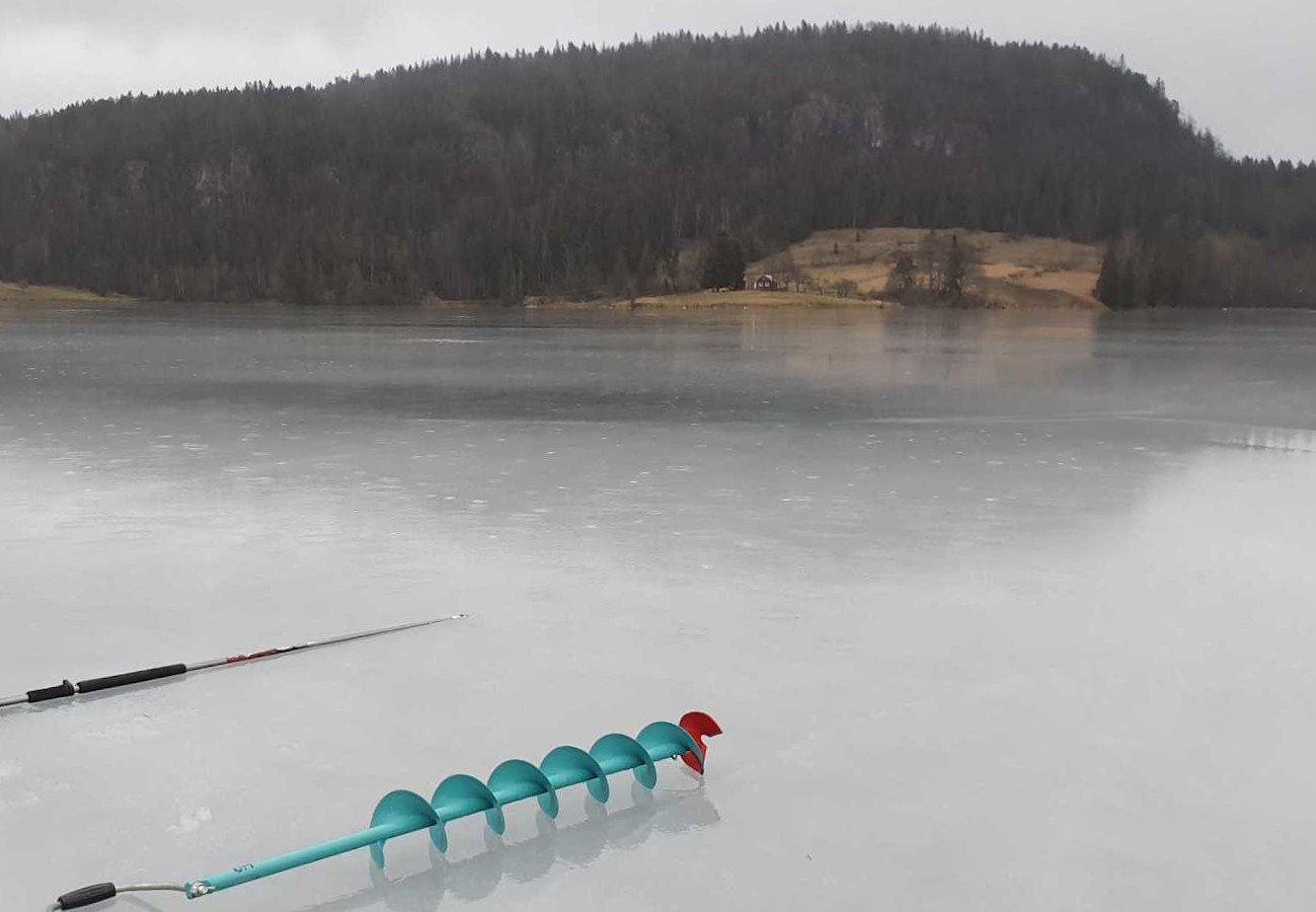 Bilde av islagt vann med isstav og isbor på.