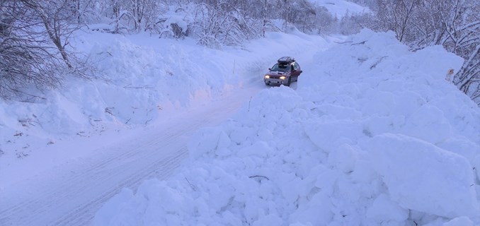 En bil som står parkert på en vei hvor det har gått et snøskred over.