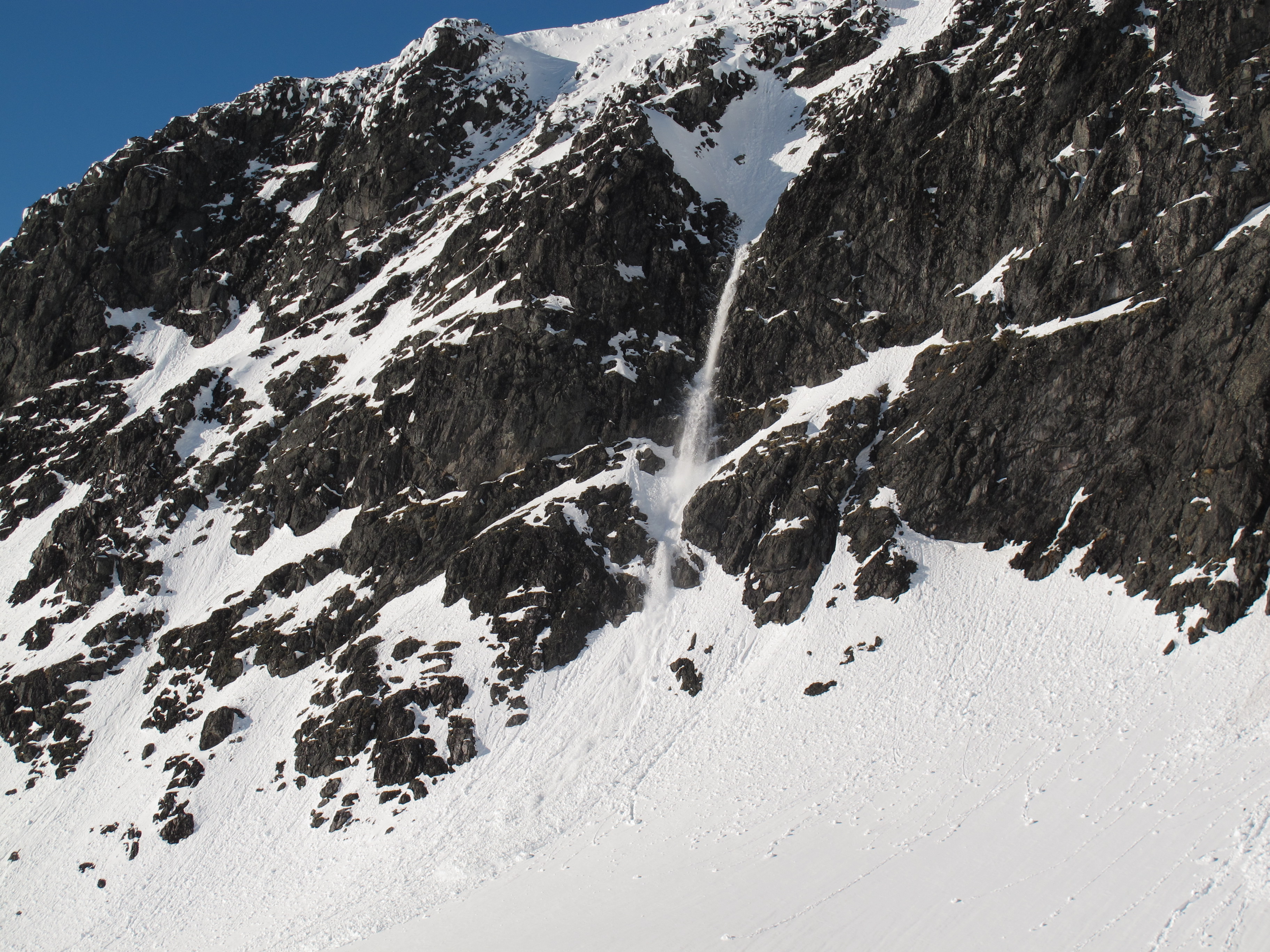 Et vått løssnøskred kommer ned fra bratt fjell i Hurrungane.