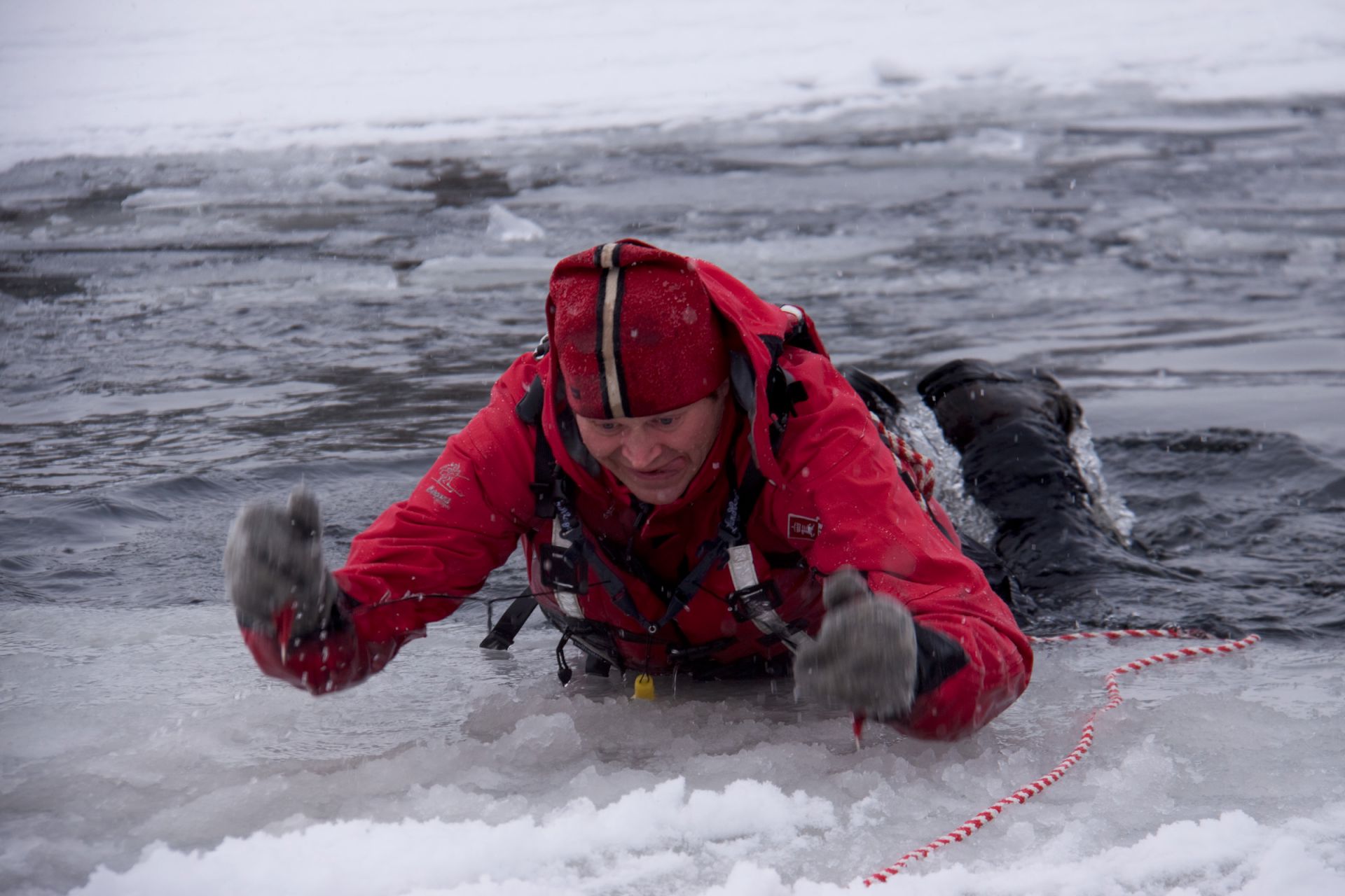 En person som bruker ispigger til å dra seg opp på isen.
