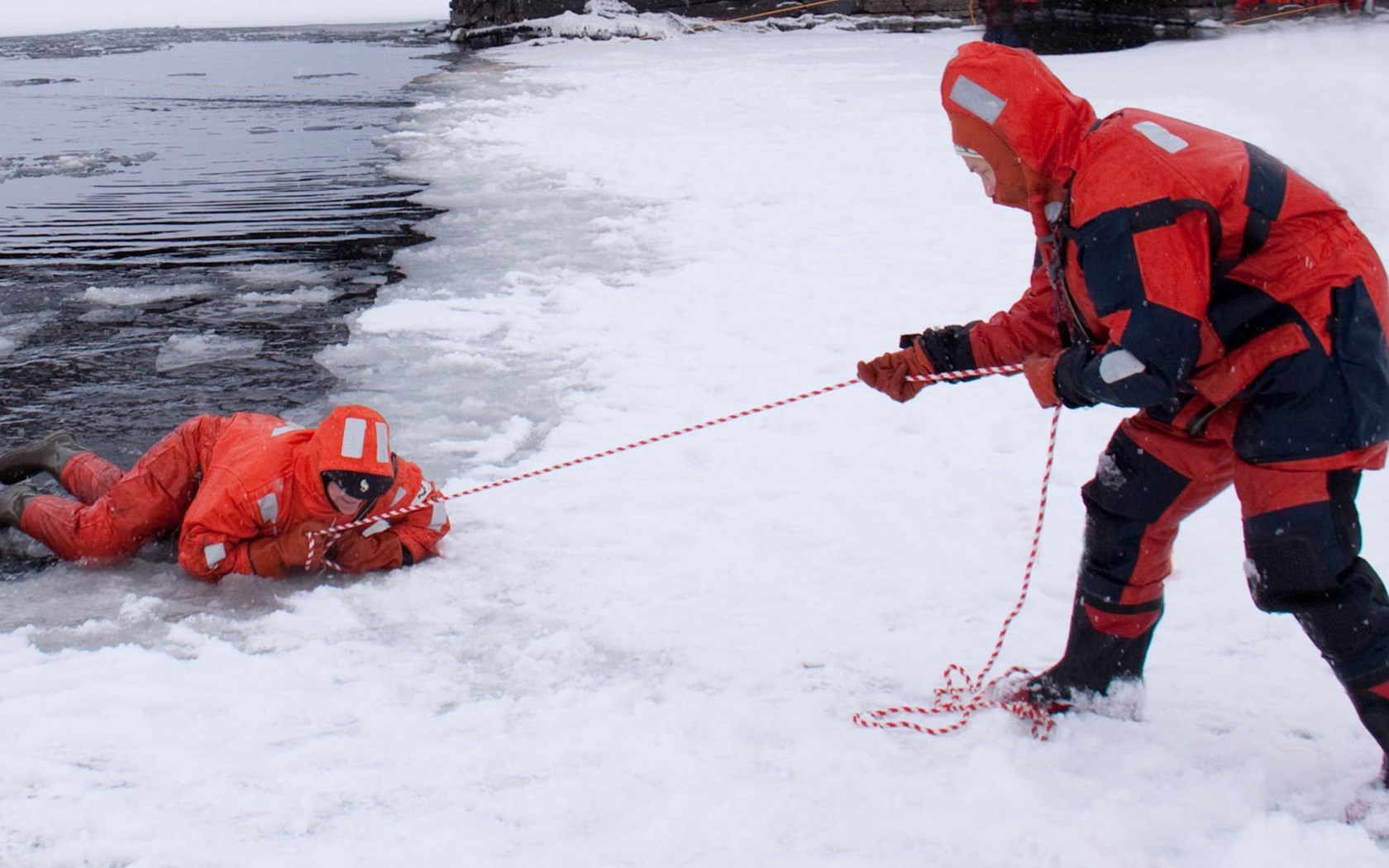 En person blir dratt opp på isen ved hjelp av en kasteline.