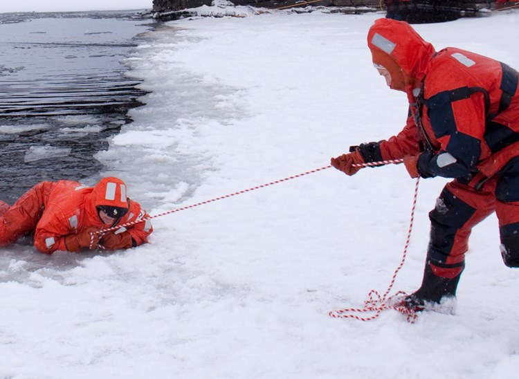 En person blir dratt opp på isen ved hjelp av en kasteline.