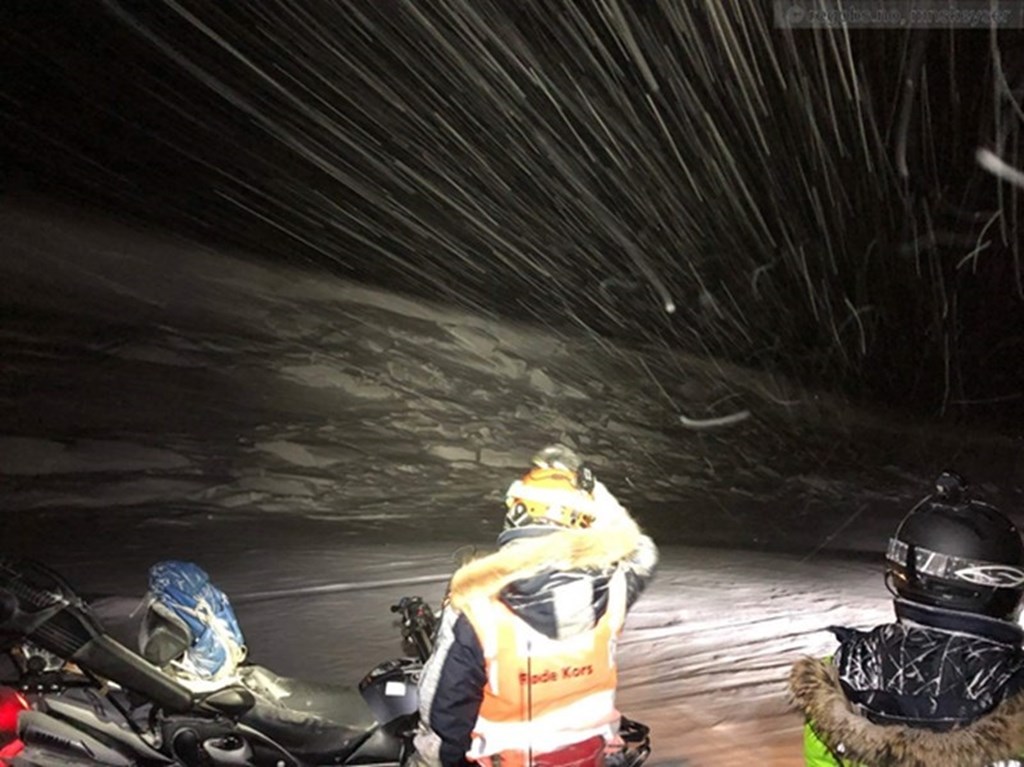 person in red cross safety vest in snow at night