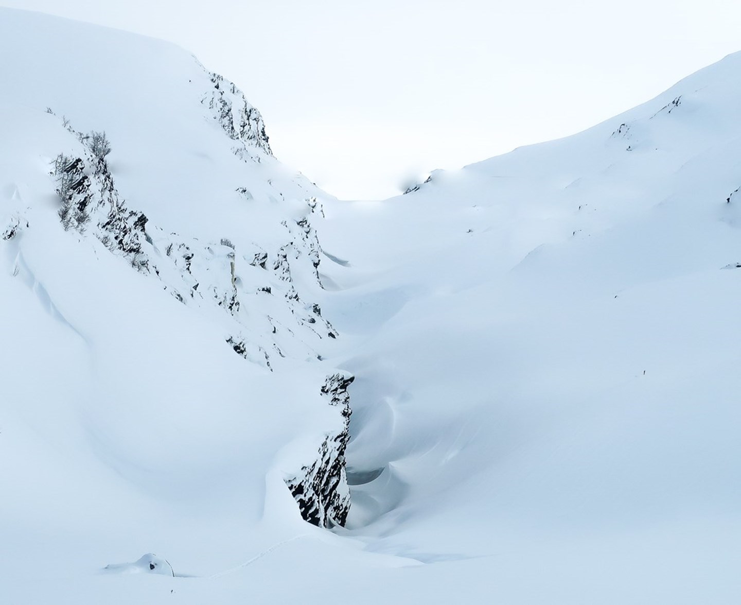 En bekkedal fylt av snø og hvor det er bratt på begge sidene.