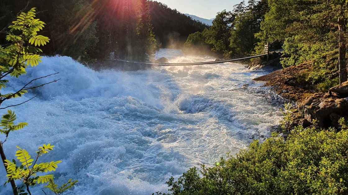 Hengebru over elv med stor vannføring.